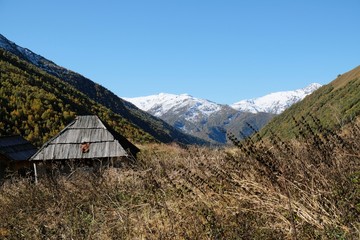 Fototapeta na wymiar Mountain landscape with wooden shepherd's huts in valley and Maphkrani Mountain Range in background. During trekking to Khalde glacier. Greater Caucasus, Svaneti, Georgia