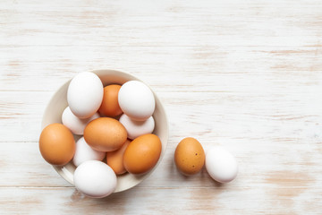 Free-range organic brown and white eggs in bowl on wood background with copy space