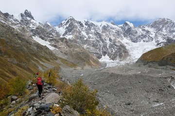 Fototapeta na wymiar The tongue of glacier Khalde is covered with debris. Snowy peaks Dzhangi-Tau and Shkhara in background. During trekking from Khalde to Khalde glacier. Greater Caucasus, Svaneti, Georgia
