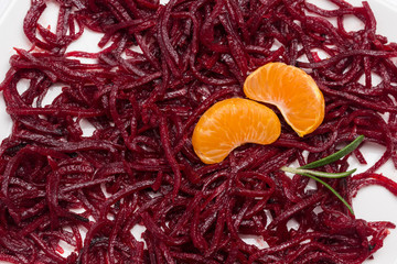 Two slices of mandarin on sliced fermented beets.