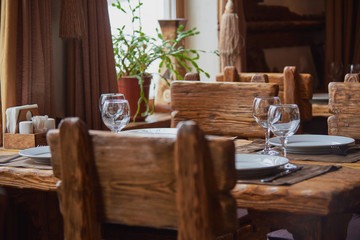 A textured wooden table by the window, set for dinner.Selective focus.