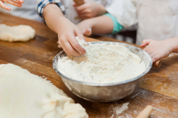  children's hands take flour from the bowl