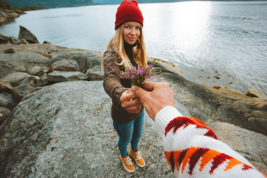 Hand giving flowers to girlfriend couple romantic dating outdoor relationship lifestyle vacations love concept man and woman walking on seaside