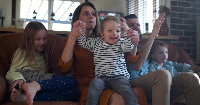 Fun family together portrait, Caucasian mother and father spend time with three kids at home on the couch slow motion.