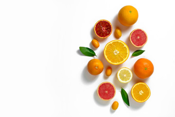 Close up image of juicy organic whole and halved assorted citrus fruits, green leaves & visible core texture, isolated white background, copy space. Vitamin C loaded food concept. Top view, flat lay.