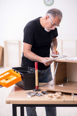 Old male carpenter working indoors