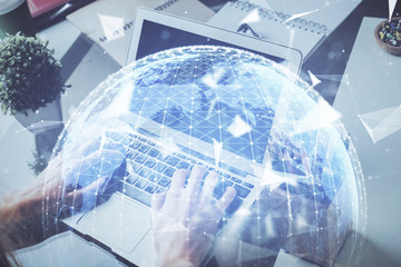 Double exposure of businessman working on laptop on background. International business hologram in front. Concept of success.