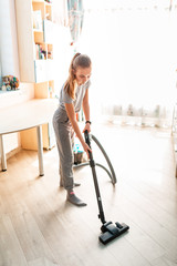 Teenage girl cleaning her room with vacuum cleaner