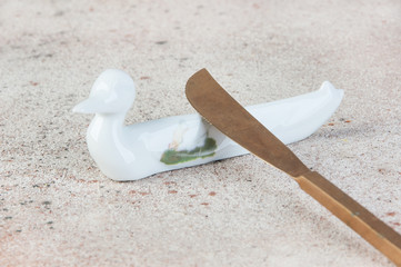 Antique porcelain duck cutlery stand on concrete background.