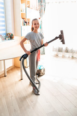 Teenage girl cleaning her room with vacuum cleaner