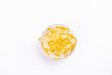 Bunch of omega 3 fish liver oil capsules in small glass bowl. Close up of golden translucent pills...