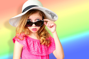 beautiful little girl in a pink dress, sunglasses and hat from the sun on a bright flat background, baby emotions, place for text