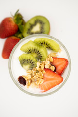 Oatmeal granola with nuts, fruit and yogurt. Strawberries and kiwis. Glass on a white background.