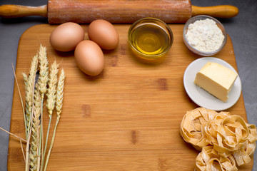 Obraz na płótnie Canvas Italian pasta on a board with some eggs, oil, flour, butter and wheat.