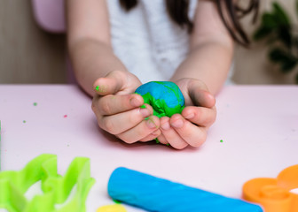 Child hands playing with colorful clay. Homemade plastiline. Plasticine. play dough. Girl molding modeling clay. Homemade clay.