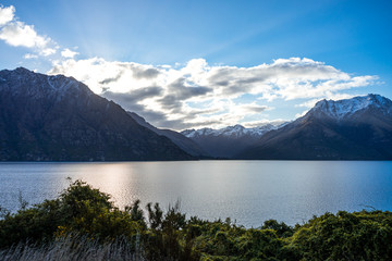 Gorgeous image of the snow capped mountains at the Wakatipu lake taken during an orange sunset in Queenstown, New Zealand