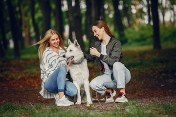 Naklejka na ściany i meble Beautiful girl in a white blouse. Women in a summer forest. Ladies with a dog