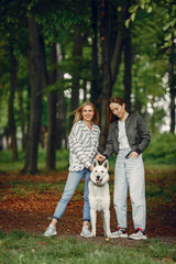 Beautiful girl in a white blouse. Women in a summer forest. Ladies with a dog