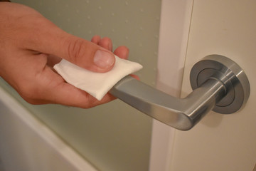 Desinfectando el mago de la puerta con una servilleta húmeda para eliminar las bacterias y los virus	