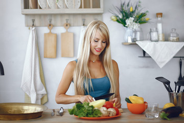 Beautiful girl make a salad. Sporty blonde in a kitchen