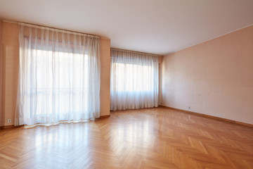 Empty large room with wooden floor and white curtains in apartment interior
