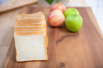 slice white bread on cutting board with apples  and banana with bowl of fresh green salad in kitchen, healthy food concept.