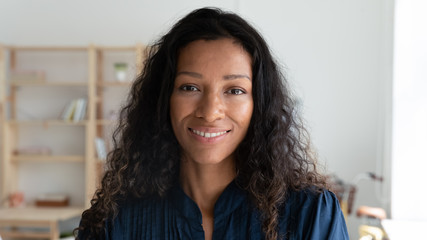 Headshot portrait of smiling african American female employee look at camera posing in modern office, happy biracial young businesswoman show confidence and motivation, work leadership concept - Powered by Adobe