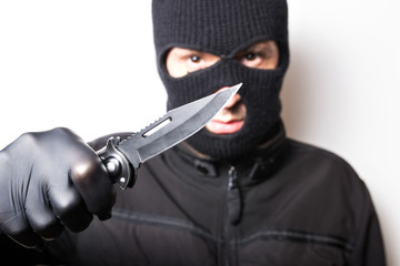 A man in a black jacket with a knife on a white background. Robbery or crime with a knife.