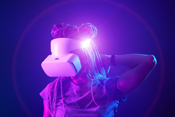 Woman is using virtual reality headset. Neon light studio portrait.