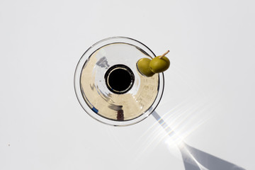 a cocktail in a white background with two olives