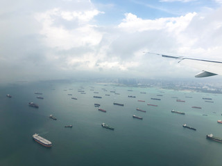 Landscape from bird eye view seascape of dense rows of cargo ship from airplane window. Cargo ships entering one of the busiest ports in the world, Singapore