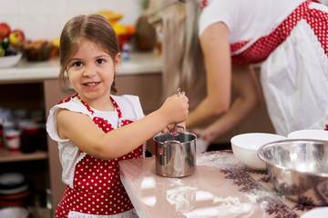 Little girl cooking with her mom
