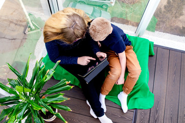 Teen girl and child boy read an e-book on a tablet. Isolation from the outside world. World quarantine, coronovirus pantemia, COVID-19. Distance learning. close-up. Children are sitting on the balcony