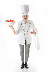 Chef cook in white uniform holds a plate with a apples on a white background