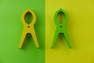 Top view of large green and yellow clothes pin on two color background which are yellow and green.