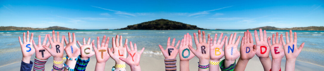 Children Hands Building Colorful English Word Strictly Forbidden. Ocean And Beach As Background
