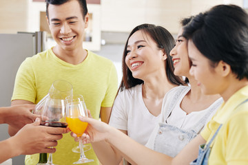 Cheerful young Vietnamese people gathered at house party for having some drinks and socializing