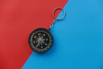 Top view of black compass on two color background which are red and blue.