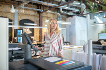 Blonde woman choosing paper printing settings, looking sideways