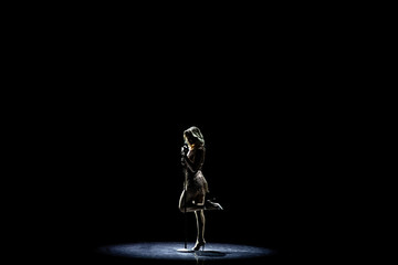 Silhouette of Beautiful good shaped blond woman singing on the stage with microphone
