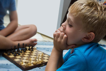 Two young boys playing chess. The one child is thinking very hard about he`s next move.