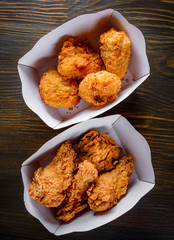 Fried breaded chicken in white cardboard box on wooden table background