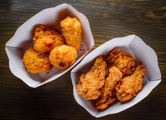Fried breaded chicken in white cardboard box on wooden table background