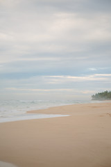Fototapeta na wymiar The coast of the Indian Ocean at dawn in Sri Lanka in March 2020. Calm beautiful water and azure blue waves
