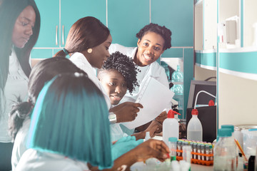 Obraz premium Female African medical students, young graduates or doctors discuss ongoing development of Covid-19 vaccine. Energetic expressive happy group working together in research facility.