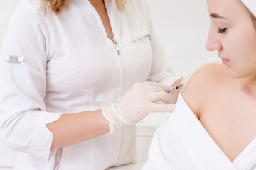 Young unidentified woman immunologist doctor vaccines a young caucasian girl. Vaccine ambiguous...