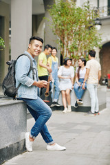 Fototapeta premium Handsome Asian university student standing at university campus and texting friends