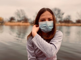 a teenage girl taking off a medical mask