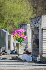 Bouquet of plastic flowers on a grave - tombstones in an European cemetery