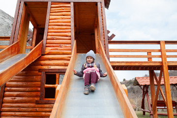 A little girl walk on a playground in an eco park against the background of a spring forest, outdoor